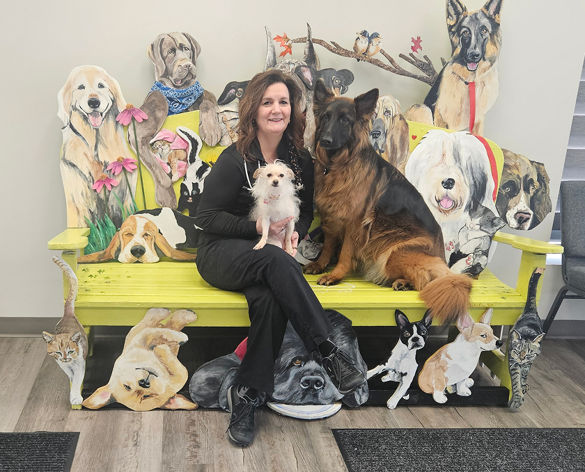 A smiling woman sits on a bench with a small white dog and a large brown dog, surrounded by colorful dog illustrations.
